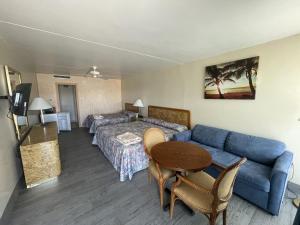 a hotel room with a couch and a bed and a table at Landmark Motel in Wildwood