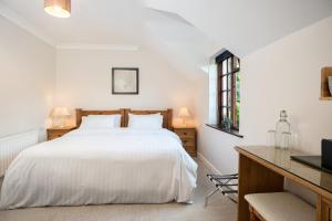 Schlafzimmer mit einem weißen Bett und einem Schreibtisch in der Unterkunft Woodside Lodge accomodation in Westport