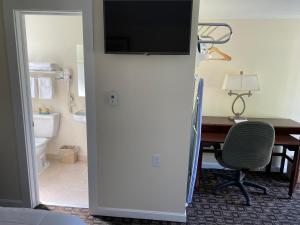 a hotel room with a desk and a television on a wall at Villager Motel in Williamstown