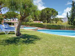 a pool with chairs and a tree in the grass at Wonderful villa in Vilamoura with barbecue and private swimming pool in Vilamoura