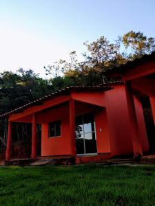 una casa roja con un césped verde delante de ella en Praia do Jatobá, en São Jorge