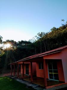 une maison rouge avec le soleil en arrière-plan dans l'établissement Praia do Jatobá, à Sao Jorge