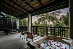 a balcony with a tub and chairs and palm trees at KC Grande Resort Koh Chang in Ko Chang