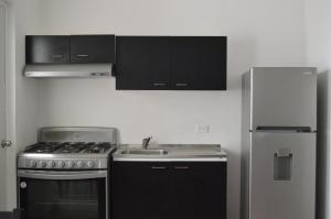 a kitchen with a stove and a refrigerator at Casa MEXH Veredas - Ideal para familias, vacaciones o homeoffice in Puerto Morelos