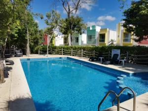 a swimming pool with blue water in front of a building at Casa MEXH Veredas - Ideal para familias, vacaciones o homeoffice in Puerto Morelos