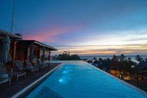 a resort swimming pool with chairs and the ocean at KC Grande Resort Koh Chang in Ko Chang