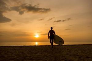a man walking on the beach with a surfboard at KC Grande Resort Koh Chang in Ko Chang
