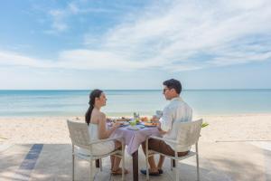 a family sitting on a beach with a picnic table at KC Grande Resort & Spa - SHA Extra Plus in Ko Chang
