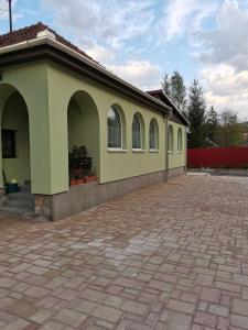 a building with two windows and a brick driveway at Halász Vendégház in Szilvásvárad