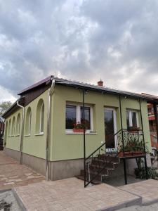 a green house with a staircase in front of it at Halász Vendégház in Szilvásvárad