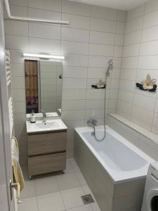y baño blanco con bañera, lavamanos y bañera. en Pingvin Cukrászda Apartman, en Balatonmáriafürdő