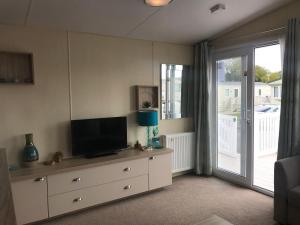 a living room with a tv on a dresser and a sliding door at Hoburne Beach Escape near Christchurch in Mudeford