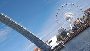 a large ferris wheel next to the water with people on it at Pokoje Sobie na Wyspie in Gdańsk