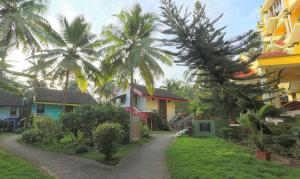 une passerelle devant certains bâtiments avec des palmiers dans l'établissement Miramar Residency, à Panaji