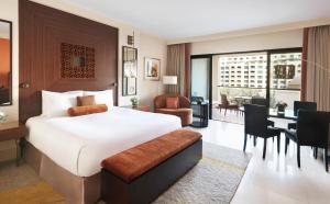 a hotel room with a bed and a dining room at Fairmont The Palm in Dubai