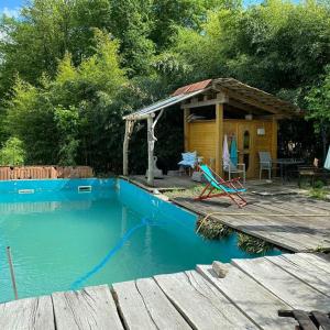 uma pequena casa com uma piscina azul e um deque de madeira em Scheunenloft- Hideaway - Ruheoase -Pool em Pirching am Traubenberg