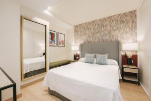 a bedroom with a white bed and a large mirror at Debambú Atarazanas in Málaga