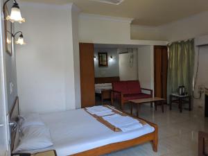 Habitación de hotel con cama y silla en Farmagudi Residency en Ponda