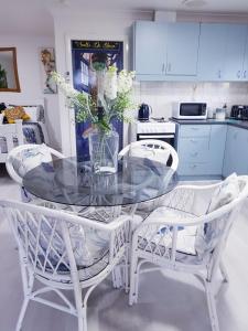 a glass table with two chairs and a vase with flowers at Black Sheep Cottage Hay in Hay +14 photos