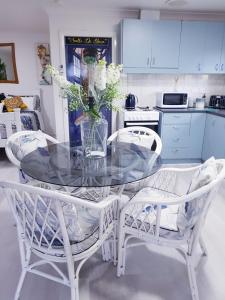 una mesa de cristal con 2 sillas y un jarrón con flores en Black Sheep Cottage Hay en Hay