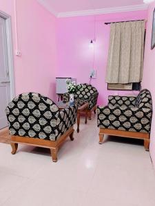 a living room with three chairs and a pink wall at Margao Residency in Madgaon