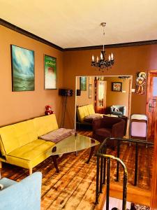 uma sala de estar com um sofá amarelo e uma mesa de vidro em Бургасский дом em Burgas