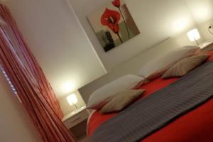 Schlafzimmer mit einem Bett mit roter Bettwäsche und Kissen in der Unterkunft Flowers house on the island in Žman