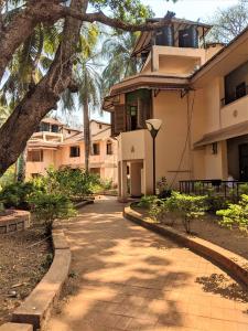 a walkway in front of a building with a tree at Old Goa Residency in Old Goa