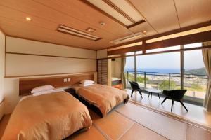 two beds in a bedroom with a view of the ocean at Atami Fuga in Atami
