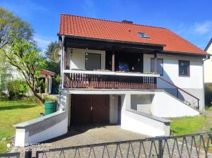 a white house with a red roof and a balcony at Waldhus in Ueckeritz