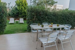 a white table and chairs in a garden at Arsinoi Studios and Apartments in Kalamaki
