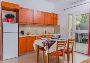 Arsinoi Studios and Apartments في كالاماكي: مطبخ مع طاولة وثلاجة بيضاء
