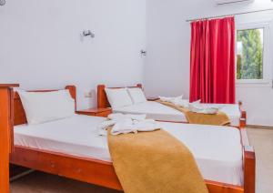 three beds in a room with a red curtain at Arsinoi Studios and Apartments in Kalamaki