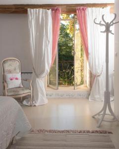 1 dormitorio con cama, ventana y silla en Sinti, en Saint-Hilaire-dʼOzilhan