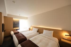 a hotel room with two beds and a television at Hakata Tokyu REI Hotel in Fukuoka +58 photos