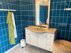 a blue tiled bathroom with a sink and a mirror at Goodnight Randers in Randers