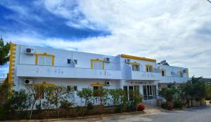 a white building with yellow windows on a street at Arsinoi Studios and Apartments in Kalamaki