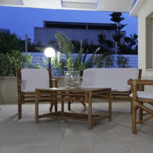 een houten salontafel en 2 stoelen op een patio bij COSTA FENICIA RESIDENCE Prenotabile da Sabato a Sabato in Scoglitti