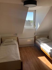 twee bedden in een kleine kamer met een raam bij Laura-haus in Vonyarcvashegy