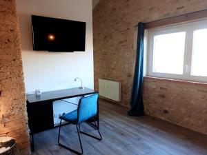 a room with a desk with a chair and a television on the wall at Les Chambres de Lili in Saint-Loup