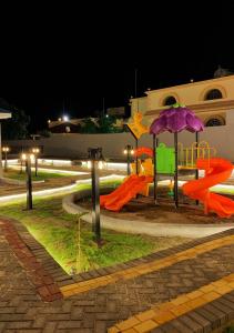 um parque infantil com escorrega e um guarda-chuva à noite em بيات للنزل السياحية em Al Qarāḩīn