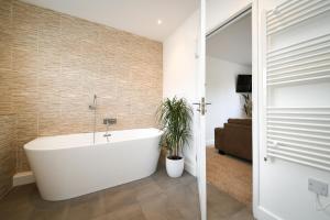 a bathroom with a white tub and a couch at Lakeside Old Hunstanton in Hunstanton
