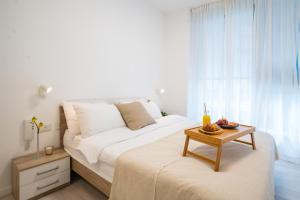 a white bedroom with a large bed and a table at Deluxe Apartment in Top Tel Aviv Neighbourhood by Sea N' Rent in Tel Aviv