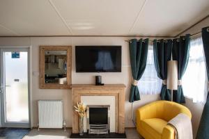 a living room with a yellow chair and a fireplace at Stunning 2 Bed Chalet in Silversands Lossiemouth in Lossiemouth