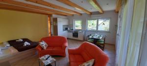 een woonkamer met 2 oranje stoelen en een keuken bij Apartment Murka in Begunje na Gorenjskem