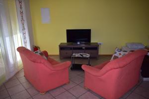 a living room with two red chairs and a tv at Apartment Murka in Begunje na Gorenjskem