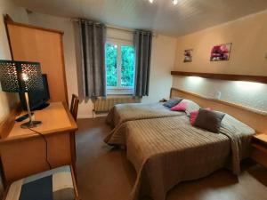 Habitación de hotel con 2 camas y TV en La Bonne Auberge en Ségny
