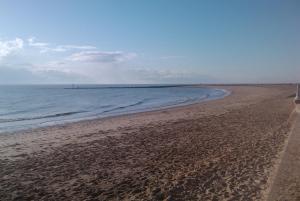 a beach with footprints in the sand and the ocean at Seaside Cottage in Clacton-on-Sea