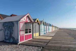 a row of colorful beach huts on a boardwalk at Maison de pêcheur à 10 minutes de la plage à pieds in Cayeux-sur-Mer