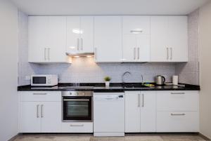 a white kitchen with white cabinets and a microwave at Palm Mar de LUX A32 in Palm-mar